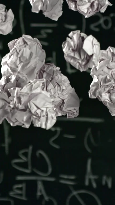Crumpled paper rises and falls against the background of the blackboard. Filmed Stock Footage 335364499
