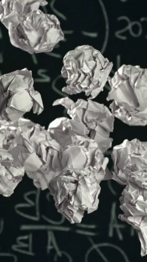 Crumpled paper rises and falls against the background of the blackboard. Filmed Stock Footage 335365438