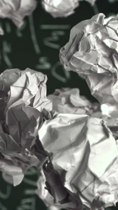 Crumpled paper rises and falls against the background of the blackboard. Filmed Stock Footage 335373222