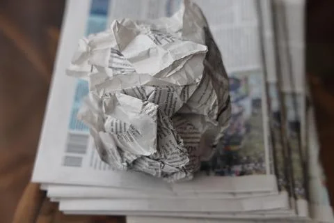 A crumpled sheet of newspaper lies on a stack of fresh newspapers, fake news, Stock Photos