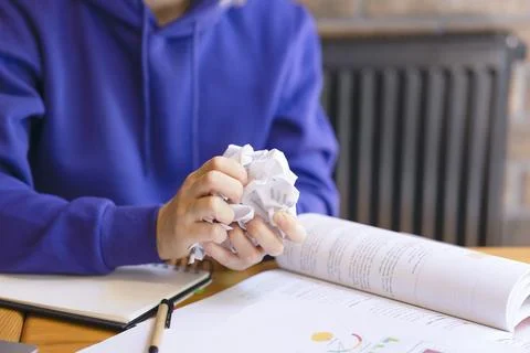 Crumpled sheet of paper in hands close-up, girl in blue sweater. Stock Photos