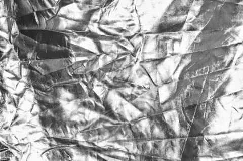 Crumpled silver reflector fabric backdrop. Monochrome black and white photo Stock Photos