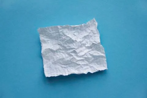 Crumpled square white checked paper sheet on on blue background  Stock Photos