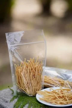 Crunchy fried snacks in clear plastic bag on stone outdoors 스톡 사진