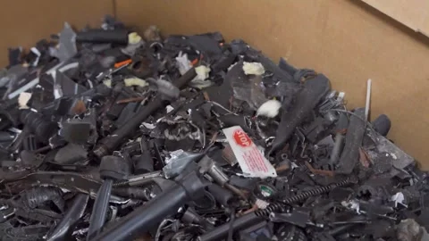Crushed and destroyed firearms fall into a hopper Stock Footage 333680862