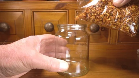 Crushed chilli seeds being picked up and poured into a glass jar. Stock-Footage 90648284