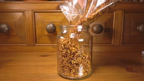 Crushed chilli seeds being poured into a glass jar. Stock-Footage 90648246