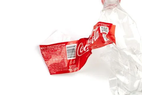 Crushed Coca-Cola plastic bottle representing environmental waste and recycli Photos