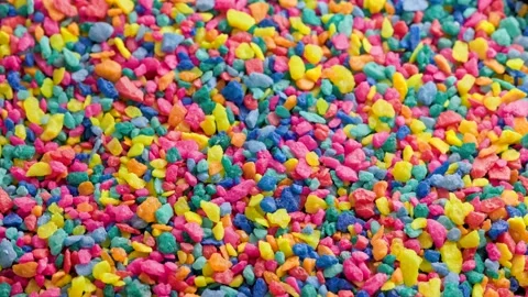 Crushed colored stones on flat surface, slowly spinning, loopable closeup Video stock 174665725