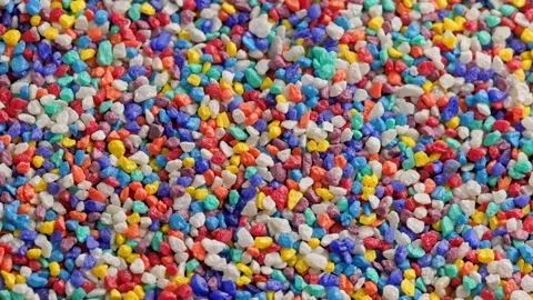 Crushed colored stones on flat surface, slowly spinning, loopable closeup Video stock 176528573