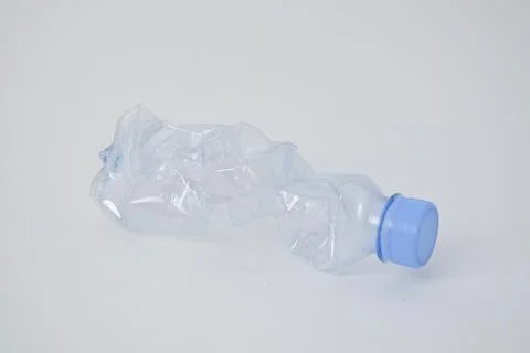 Crushed, empty clear plastic water bottle with a blue cap isolated on a whi.. Stock Photos