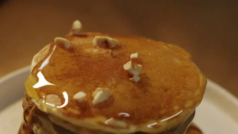 Crushed forest hazelnuts sprinkled on top of honey on a slide of pancakes 스톡 동영상 151362050