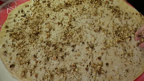 Crushed nuts being sprinkled over flattened dough, Stock Footage 336601982