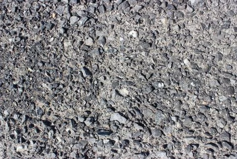 Crushed old asphalt pavement. Small gray-black pebbles. Stock Photos