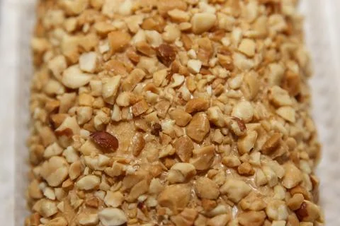 Crushed peanut-covered dessert surface texture in warm lighting. Stock Photos