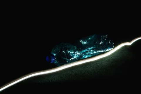 Crushed Plastic Bottle with Blue Cap on Black Background at 45-Degree Angle Stock Photos
