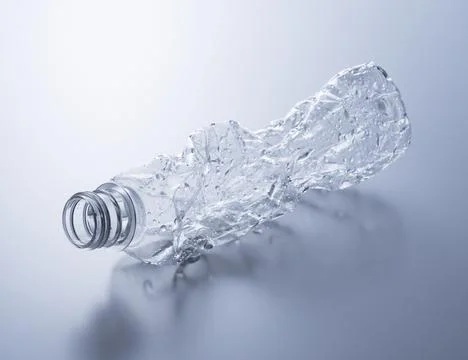 A crushed plastic bottle on a gray background. Stock Photos