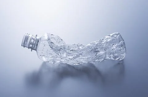 A crushed plastic bottle on a gray background. Stock Photos