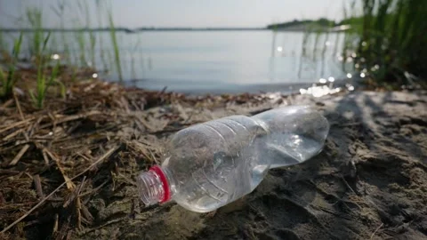 Crushed Plastic Bottle Polluting Sandy Shoreline Beside Lake Water Stockbeeldmateriaal 343573096