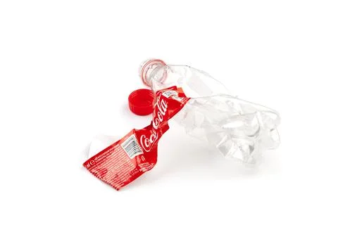 Crushed plastic Coca-Cola bottle with red cap Stock Photos