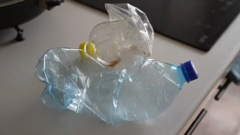 Crushed plastic water bottle lying inside a white plastic bag Stock Footage 332580209