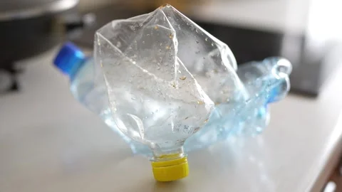 Crushed plastic water bottle lying inside a white plastic bag Stock Footage 332580211
