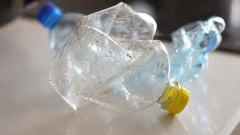 Crushed plastic water bottle lying inside a white plastic bag Stock Footage 332580214