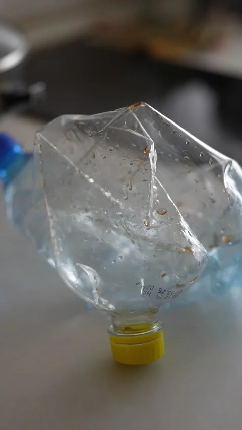 Crushed plastic water bottle lying inside a white plastic bag Stock Footage 332580219