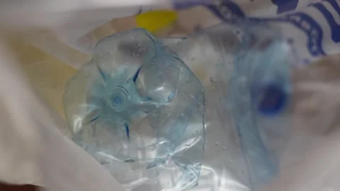 Crushed plastic water bottle lying inside a white plastic bag Stock Footage 332580357