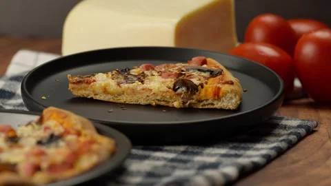 Crushed red pepper flakes falling onto a slice of mushroom and ham pizza Stock Footage 282563003