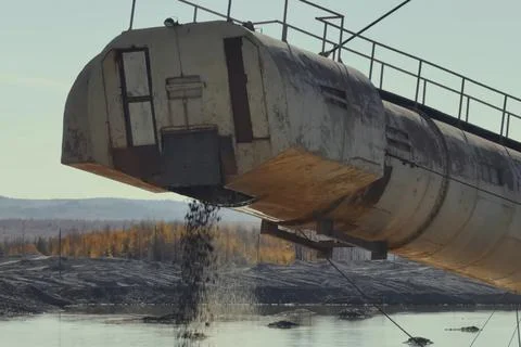 Crushed rock being ejected from the discharge chute of a multi-bucket excavat Stock Photos