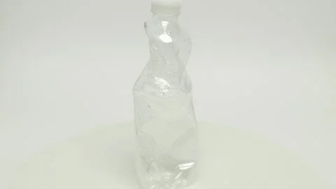 A Crushed Transparent Plastic Bottle on a Clean White Background, showcasing its Video stock 282377352