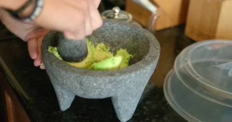 Crushing avocados into guacamole paste in a molcajete (mortar and pestle) Stock Footage