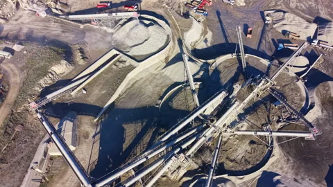 Crushing machinery operates at a large mining site during daylight, showcasing Stock Footage 332009680