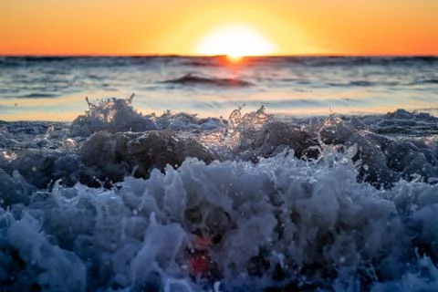Crushing waves with a setting sun in the background Photos
