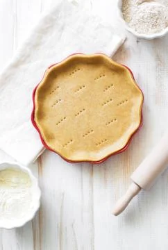 Crust on baking sheet , pots with wheat and bran flour and rolling pin on whi Stock Photos
