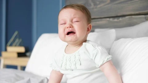 Crying baby sitting on bed Video stock 89798648