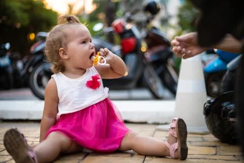 Crying child being given a pacifier by an adult Stock Photos