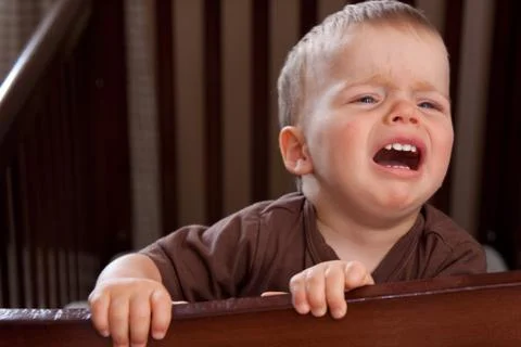 Crying child in a crib Stock Photos