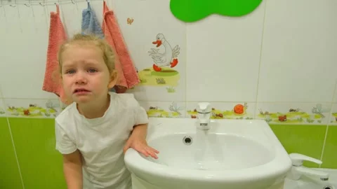 Crying child standing at sink in bathroom. Little girl feels sad while wash.. Stock Footage 333563824