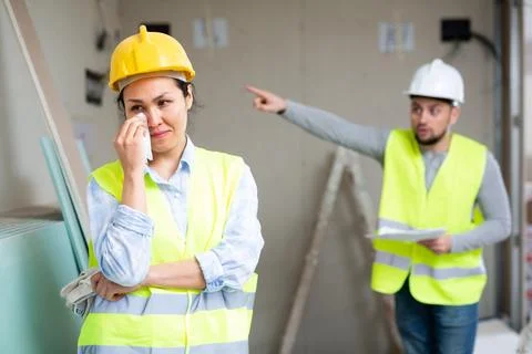 Crying female builder at construction site with displeased foreman Stock Photos