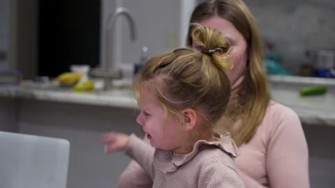 Crying girl interferes with the moms work on laptop. Woman tries to distract Stock Footage 168566070