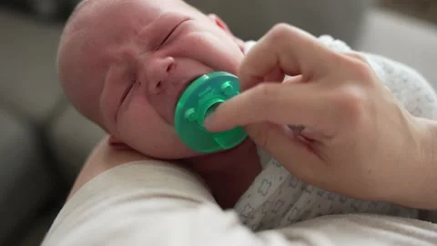 Crying infant baby calms down when mom puts pacifier in his mouth Stock Footage 197481735