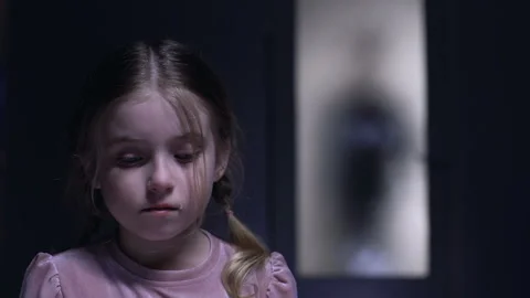 Crying little girl looking at camera silhouette of alcoholic father outside door Video stock 108759751