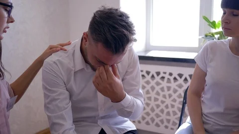 Crying man talking about problems on group therapy session sitting on chairs in Stock Footage 95531173