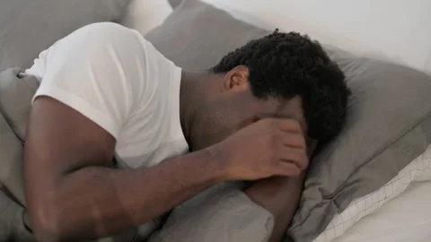 Crying Sad African Man Lying in Bed 動画素材 299756869