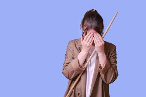 Crying woman teacher with pointer on studio blue background, copy space Stock Photos
