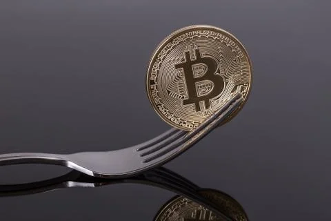 Crypto coin bitcoin in fork with reflection. Close-up. Stock Photos