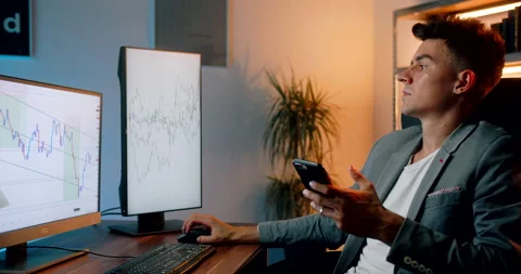 Crypto day trader checking stock charts and using app on his smartphone Stock Footage 160986215