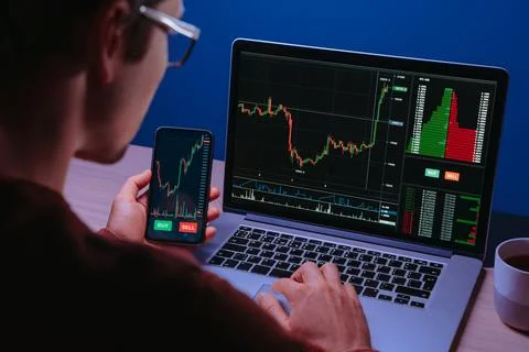 Crypto trader analyzing live cryptocurrency and stock charts on smartphone Stock Photos